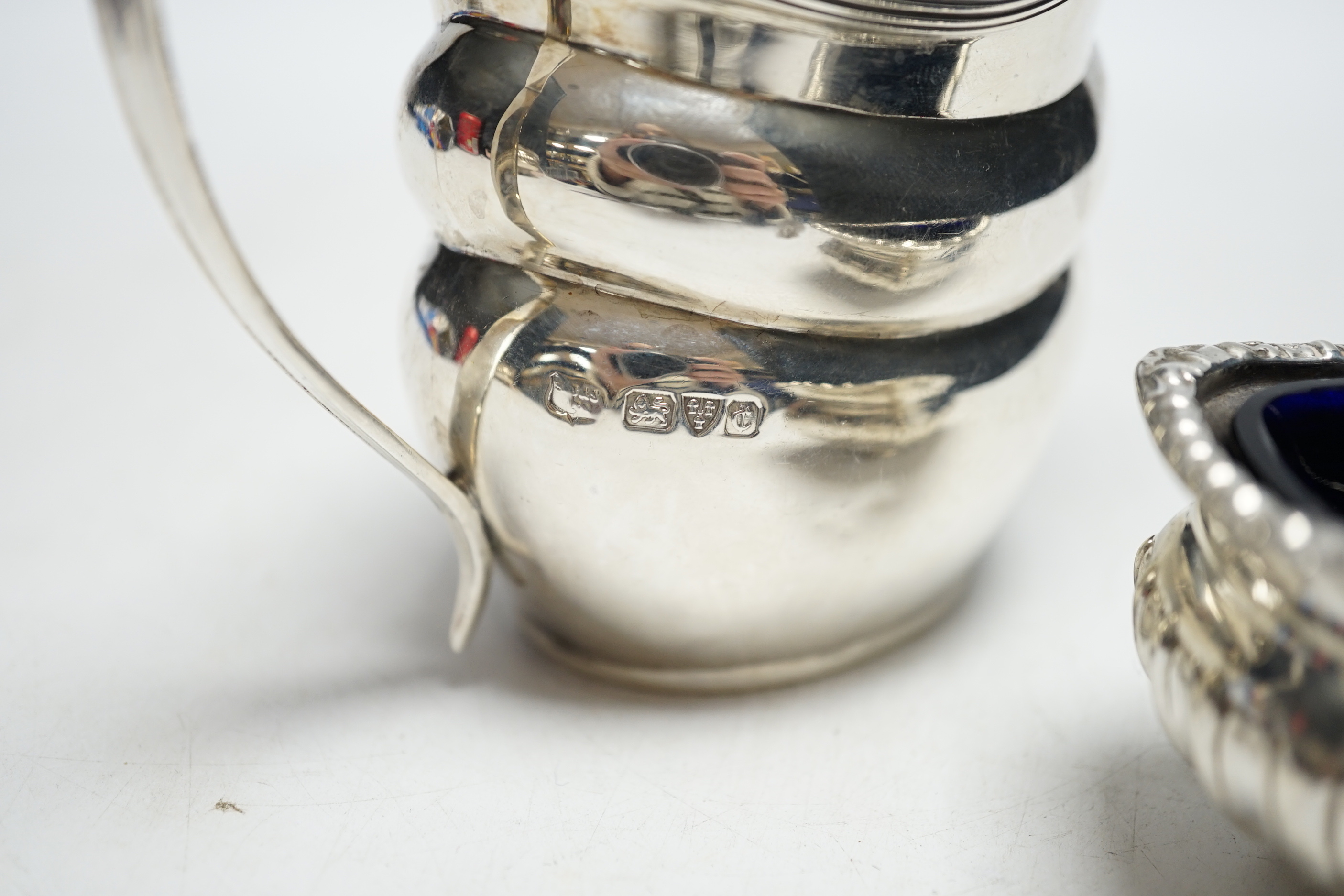 A George V silver helmet shaped cream jug and a silver salt with a gadrooned border.